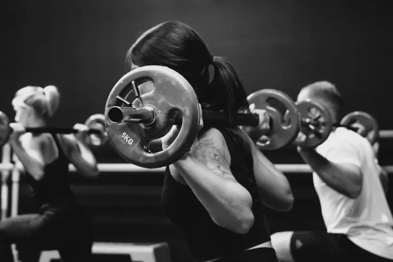 A pair of rubber hex dumbbells resting on a gym mat in a home gym setting