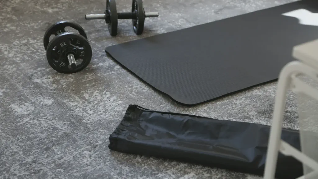 A compact home strength-training setup with dumbbells stored neatly beside an exercise mat in a small apartment