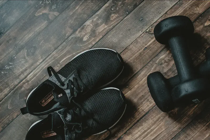 Compact home strength-training area with dumbbells stored neatly beside an exercise mat